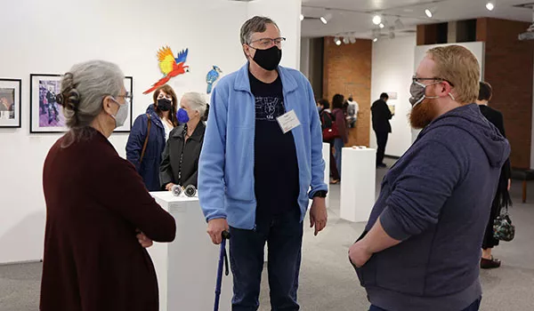 Sven Anderson talks with former students and others at the opening reception for his exhibit.