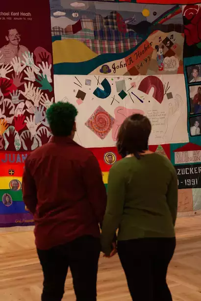 Two people holding hands looking at the National AIDS Memorial Quilt display