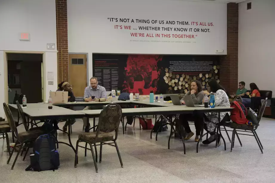 Faculty sitting at a square classroom style desk learning about inclusive pedagogies during a Faculty Academy 