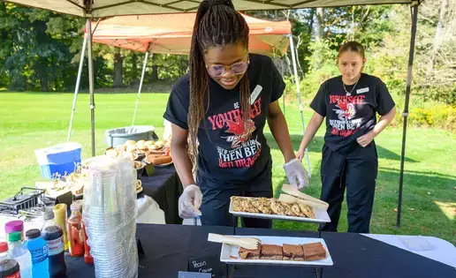 Food service major places trays of food on table at Red Dragon Open